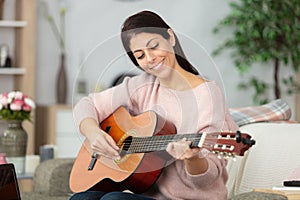 cheerful woman playing guitar at home