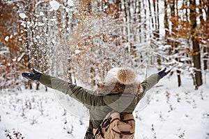 Cheerful woman playing with snow at winter forest