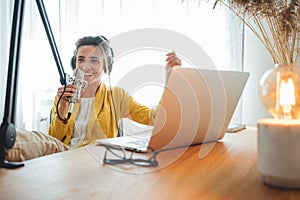 Cheerful woman podcaster recording her voice into microphone