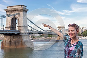 Cheerful woman pointing to Chain Bridge at Budapest, Hungary
