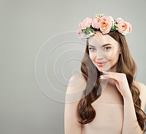 Cheerful woman portrait. Young model with clear skin, long healthy curly hair and flowers. Skincare and facial treatment concept