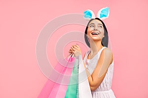 Cheerful woman in rabbit ears with shopping bags in her hands, spring shopping, traditional holiday