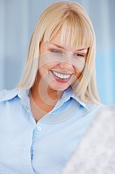 Cheerful woman reading news. Portrait of smiling woman reading newspaper.