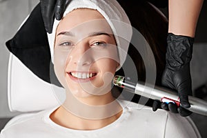 Cheerful woman receiving face rejuvenation treatment in beauty salon.