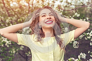 Cheerful woman rumpling hair in spring garden