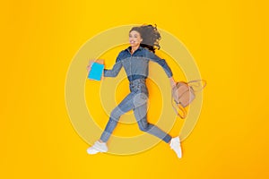 Cheerful Woman Running Holding Backpack And Copybooks Over Yellow Background