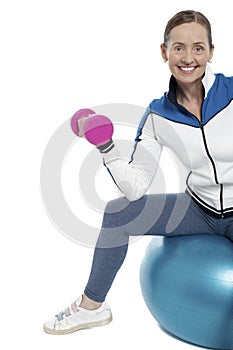 Cheerful woman seated on pilates ball and exercising