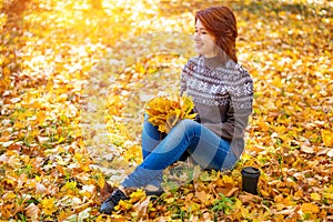 Cheerful woman sitting in the autumn Park on fallen leaves