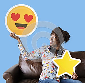 Cheerful woman holding a heart eyes emoticon and star icons