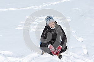 Cheerful woman squating cross-legged on snow
