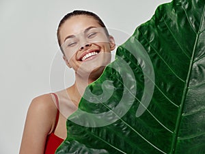 cheerful woman stands behind green leaf of palm tree clean skin model