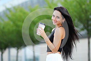 Cheerful woman in the street drinking morning coffee in sunshine