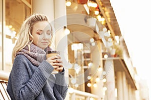 Cheerful woman in the street drinking morning coffee in sunshine light