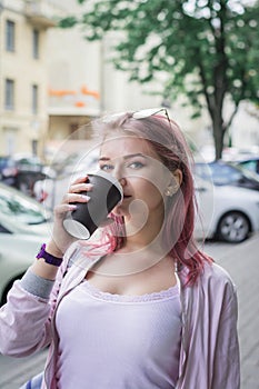 Cheerful woman in the street drinking morning coffee in sunshine light