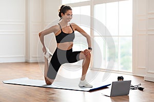 Cheerful woman stretching leg muscles using pc