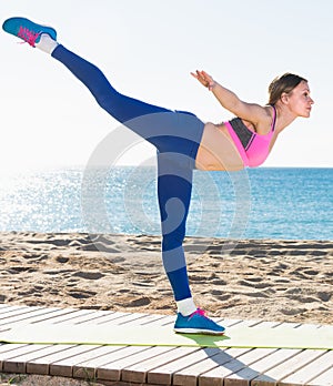 Cheerful woman stretching muscles on the sand