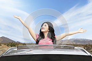 Cheerful woman on sunroof of car