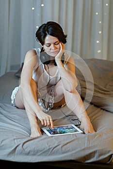 Cheerful woman with tablet on bed