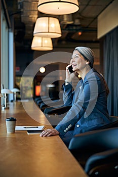 Cheerful woman talking on cellphone at business center