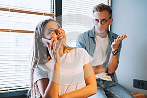 Cheerful woman talks with best friend, standing in the kitchen with husband