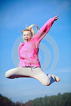 Cheerful woman teenage girl in tracksuit jumping showing outdoor