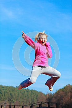 Cheerful woman teenage girl in tracksuit jumping showing outdoor