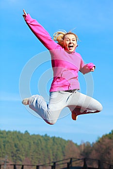 Cheerful woman teenage girl in tracksuit jumping showing outdoor