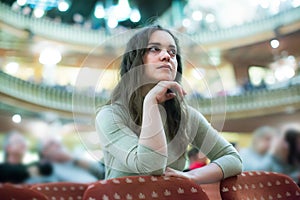 Cheerful woman theatre goer looking at play