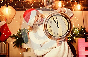 Cheerful woman.. Time to celebrate. xmas mood. Woman wi clock. girl in red santa claus hat. Midnight. winter holidays
