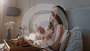 Cheerful woman typing smartphone in morning. Serene dreamy girl enjoy breakfast