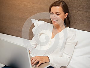 Cheerful woman using her laptop in the bedroom