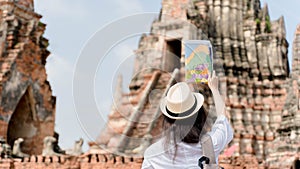 Cheerful woman wanderer with trendy look searching direction on location map while traveling temple