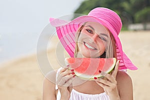 Cheerful woman wearing pink sunhat with juicy watermelon