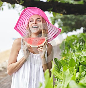 Cheerful woman wearing pink sunhat with watermelon