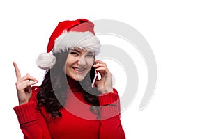 Cheerful woman wearing santa hat with exited face expression showing finger up and talking on phone, isolated with copy space