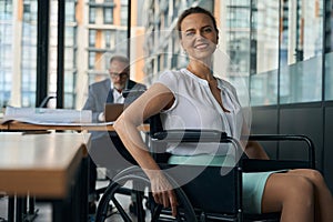 Cheerful woman in a wheelchair is in the office