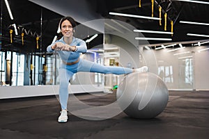 Cheerful woman working out with a fitness ball in the gym.