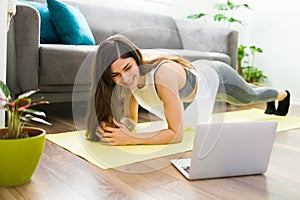 Cheerful woman working out with a video tutorial in the living room