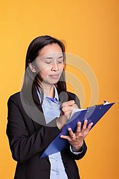 Cheerful woman writing business report on clipboard