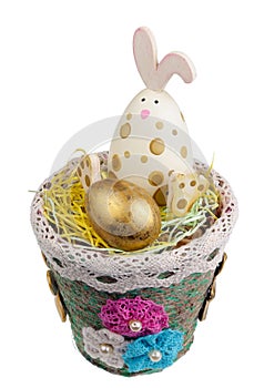 Cheerful wooden Easter bunny guards a golden quail egg isolated