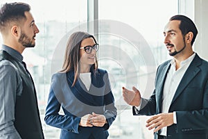 Cheerful work team during break time in office, chatting lively.