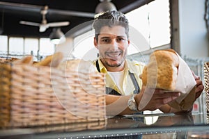 Cheerful worker standing and presenting a bread