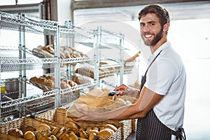 Cheerful worker standing and presenting a bread