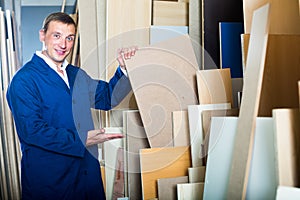 Cheerful workman standing with plywood pieces