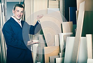 Cheerful workman standing with plywood pieces