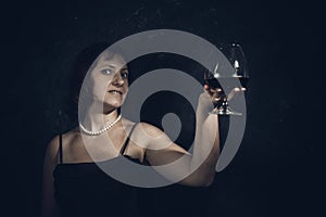 Cheerful 40 years old woman in classic dress with glass of wine