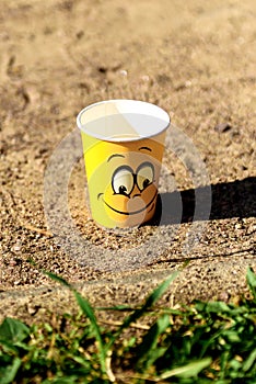 A cheerful yellow paper cup on the sand.