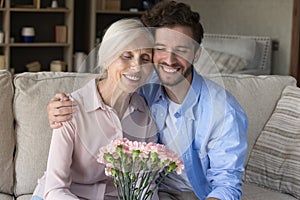 Cheerful young adult guy congratulating mom on 8 march