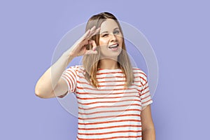 Cheerful young adult woman showing okay sign, assures you everything is fine, looks gladly.