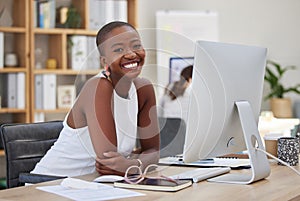 Cheerful young african american business woman smiling and working on a computer in an office. Bald female entrepreneur